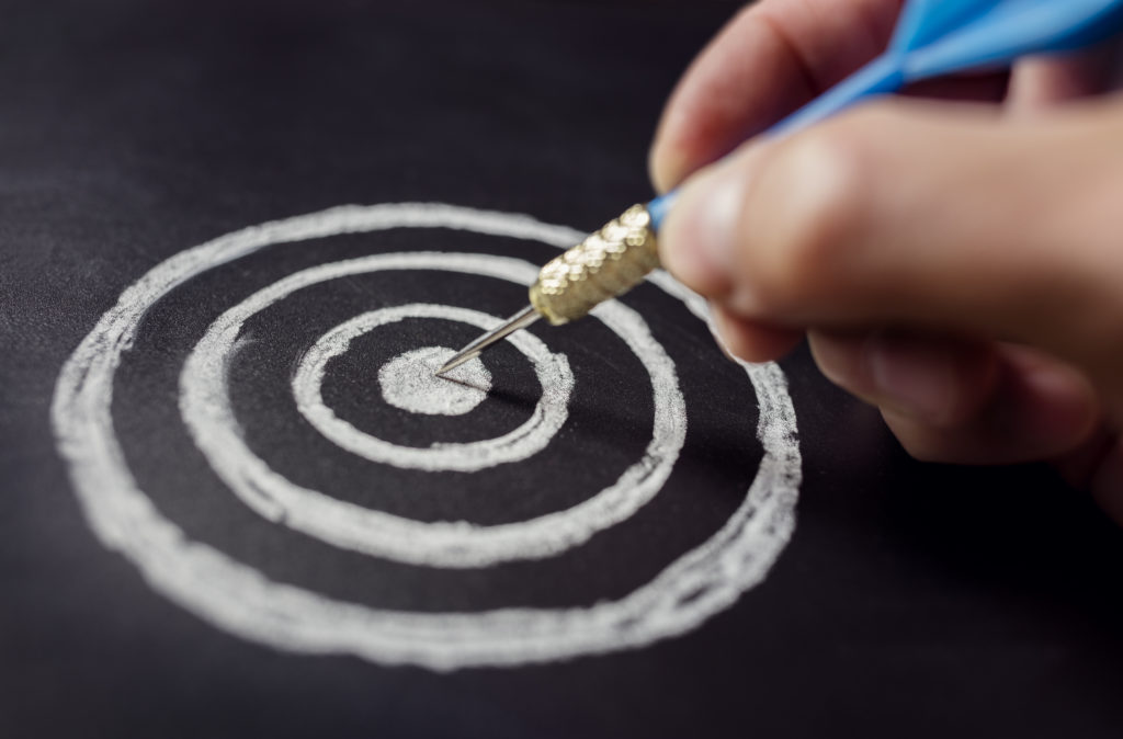 Businessman target for success holding dart on blackboard